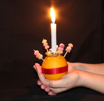A hand holding a lit candle