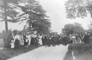 An old photo of a group of people standing next to a tree