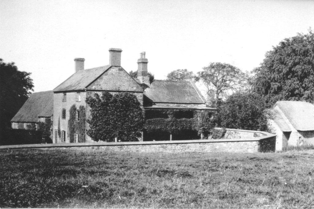 A vintage photo of an old building with grass in front of a house