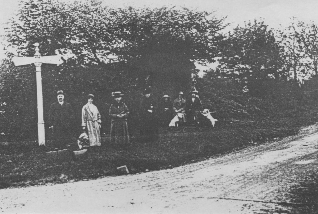 A vintage photo of a group of people walking down a dirt road