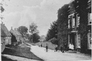 A vintage photo of a horse drawn carriage in front of a house