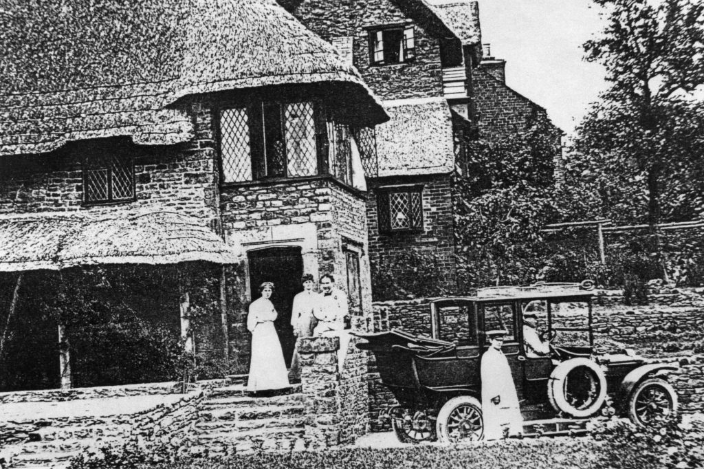 A vintage photo of a horse drawn carriage in front of a house