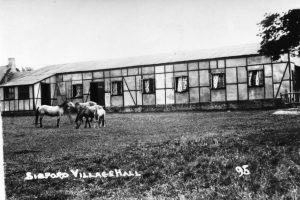A cow grazing on grass in front of a house