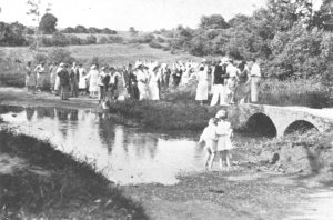A vintage photo of a group of people standing in front of a crowd