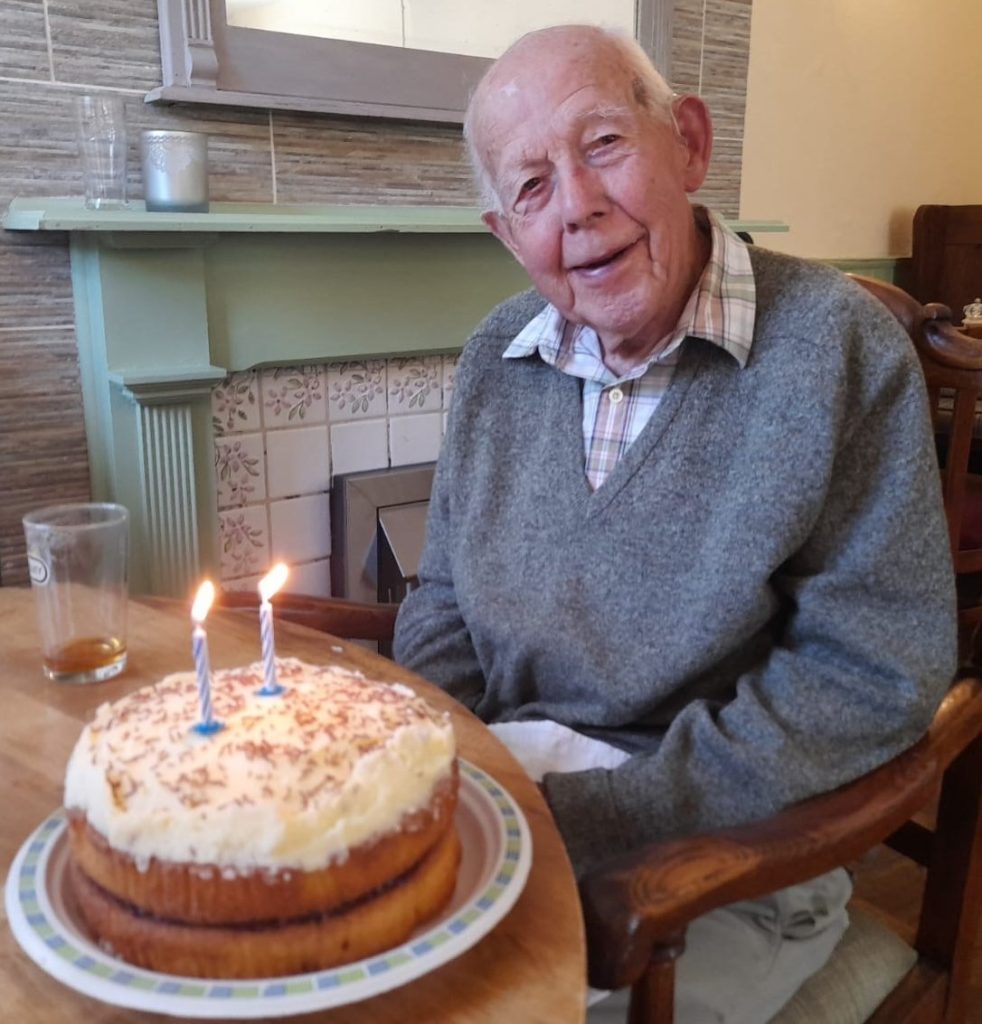 A man sitting at a table in front of a birthday cake