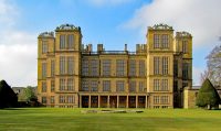 A large building with a grassy field with Hardwick Hall in the background