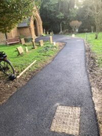 A bicycle parked on the side of a dirt road